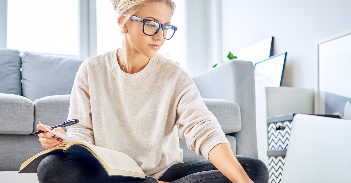 digtigardqozbllc-391030-woman-apartment-budgeting-image-a1 A young woman wearing glasses sitting on the floor with a laptop and budgeting materials scattered around her.