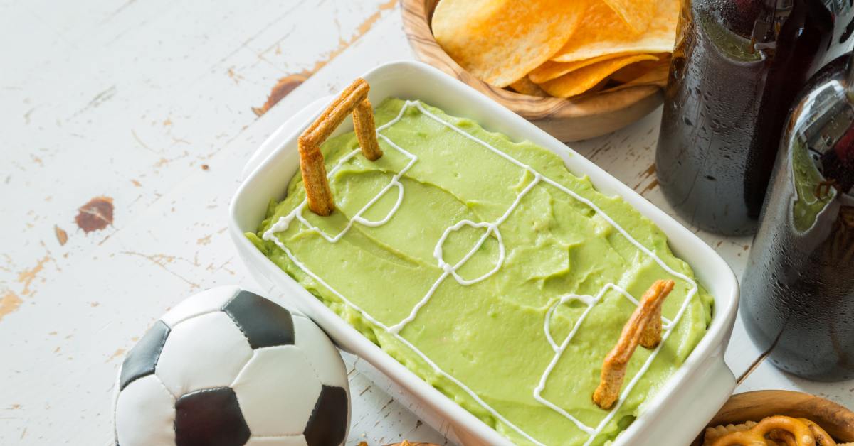 digtigardqozbllc-391038-soccer-themed-snacks-image-a1 A close-up of a spread of soccer-themed snacks on a white wooden table. A soccer ball rests next to the assortment.