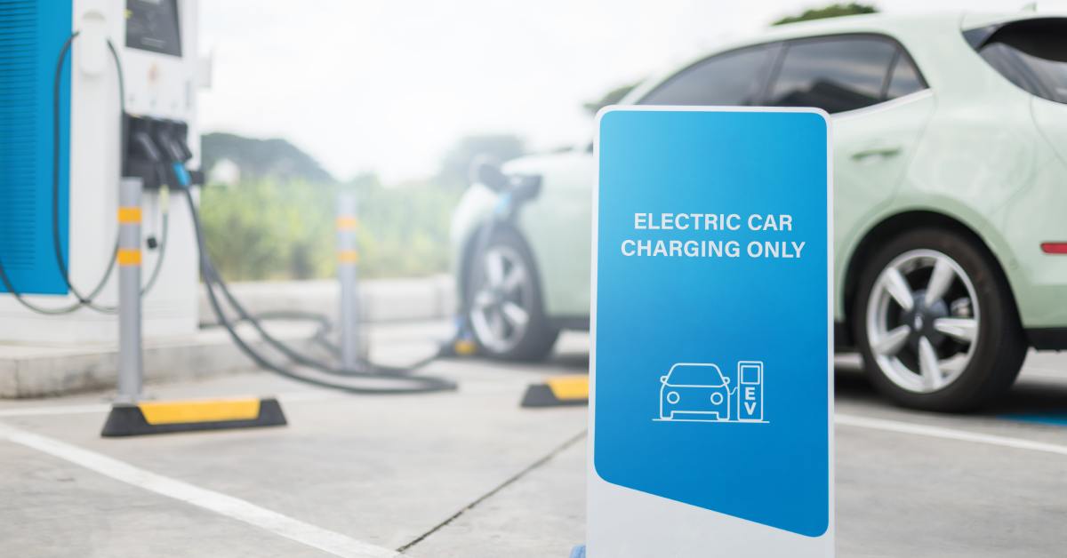 digtigardqozbllc-391041-car-charging-station-image-a1 A parking station with an EV charger and a sign in front of it that reads